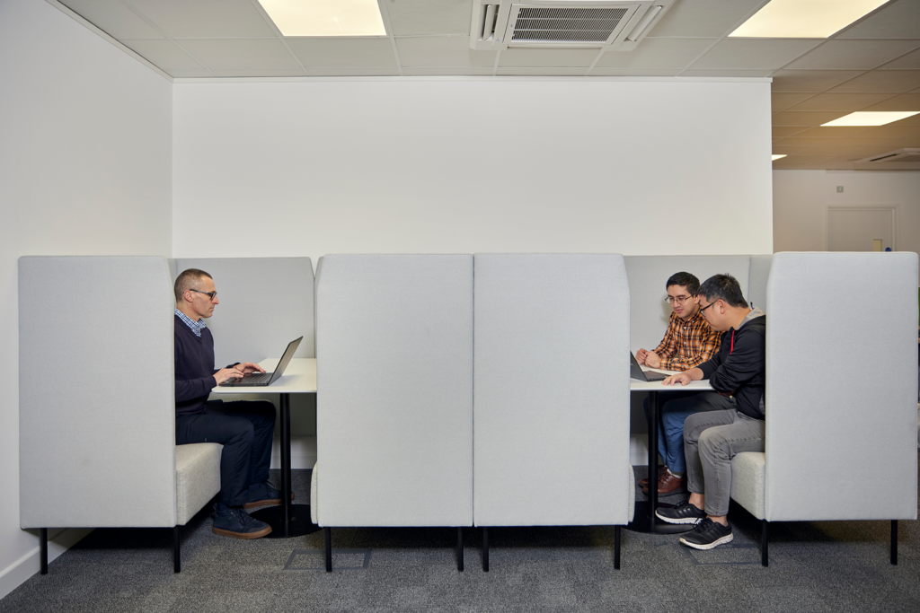 Office workers in booths facing each other